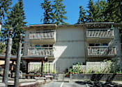 Thumbnail 1 of 5 - A white building with balconies is surrounded by trees.