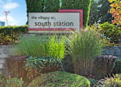Thumbnail 13 of 16 - A sign that says "The Villages at South Station" is surrounded by plants.