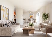 Thumbnail 6 of 27 - A living room with a grey couch, a coffee table, and a painting on the wall.