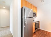 Thumbnail 9 of 27 - A kitchen with a stainless steel refrigerator and wooden cabinets.