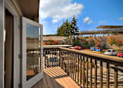 Thumbnail 1 of 16 - A view from a balcony looking out at a parking lot and a building.
