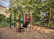 Thumbnail 7 of 16 - A playground with a red slide and green climbing frame.
