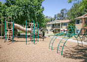 Thumbnail 2 of 20 - A playground with a green slide and monkey bars.