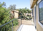 Thumbnail 10 of 20 - A balcony with a metal railing and a view of a building and trees.