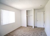 Thumbnail 13 of 20 - A room with a carpeted floor and a window with blinds.