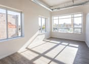 Thumbnail 2 of 34 - A sunny room with a large window and a wooden floor.