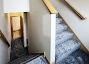 Thumbnail 11 of 30 - A staircase with a grey carpeted runner and wooden handrails.