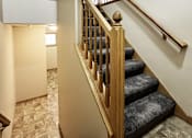Thumbnail 27 of 30 - A staircase with a wooden banister and a carpeted stair runner.