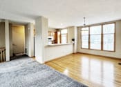Thumbnail 13 of 30 - A large, empty room with wooden floors and a grey rug.