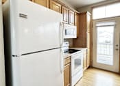 Thumbnail 3 of 30 - A white refrigerator in a kitchen with wooden cabinets.