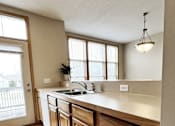 Thumbnail 2 of 30 - A kitchen with wooden cabinets and a white countertop.
