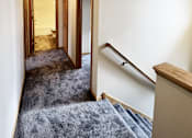 Thumbnail 25 of 30 - A hallway with a staircase and a door.