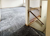 Thumbnail 23 of 30 - A room with a carpeted floor and a staircase.