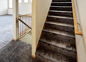Thumbnail 24 of 30 - A staircase with a carpeted runner and wooden handrail.
