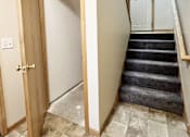 Thumbnail 26 of 30 - A wooden door is open to a hallway with a staircase.