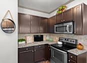 Thumbnail 6 of 59 - a kitchen with dark cabinets and stainless steel appliances at Stonepost Crossing Apartments, Overland Park, Kansas