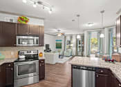 Thumbnail 5 of 59 - a kitchen and living room with wood floors and a ceiling fan at Stonepost Crossing Apartments, Overland Park, 66213