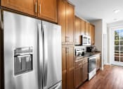 Thumbnail 3 of 50 - a kitchen with wooden cabinets and stainless steel appliances at The Dorset, Kansas City, 64112