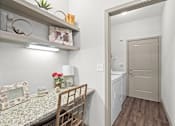 Thumbnail 10 of 59 - a dining room with a table and chairs and a laundry room in the background at Stonepost Crossing Apartments, Kansas, 66213
