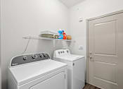 Thumbnail 11 of 59 - a laundry room with a washer and dryer next to a door at Stonepost Crossing Apartments, Overland Park, 66213