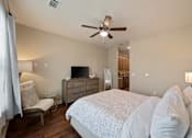 Thumbnail 49 of 50 - Guest suite bedroom at The Dorset with dresser, TV, seating chair, and view toward kitchenette area