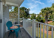 Thumbnail 8 of 14 - A blue chair sits on a porch with a view of a yard and trees.