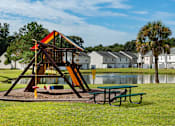 Thumbnail 9 of 10 - A playground with a slide and a picnic table at The Islands in Charleston SC