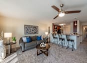 Thumbnail 1 of 11 - Living room with a grey couch, a coffee table, and a ceiling fan at Mill Creek Landing near Newport News, VA