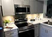 Thumbnail 1 of 14 - A kitchen with a black oven and a black microwave.