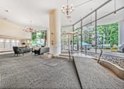 Thumbnail 4 of 19 - A large, open lobby with a grey carpet and a chandelier hanging from the ceiling.