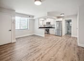 Thumbnail 13 of 27 - an empty kitchen and living room with hardwood flooring and white walls