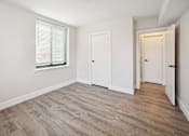 Thumbnail 18 of 27 - a bedroom with white walls and wood flooring and a window