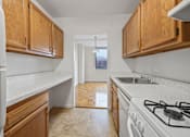 Thumbnail 18 of 19 - A kitchen with white appliances and wooden cabinets.