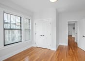 Thumbnail 6 of 22 - a living room with white walls and wood floors and a door to a hallway