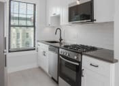Thumbnail 17 of 22 - a kitchen with white cabinets and a stove and a window
