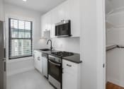Thumbnail 18 of 22 - a kitchen with white cabinets and a stove and a microwave