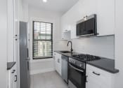 Thumbnail 15 of 22 - a white kitchen with a stove and a microwave