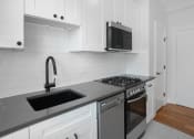 Thumbnail 19 of 22 - a kitchen with white cabinets and a sink and a stove