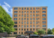 Thumbnail 22 of 22 - a tall brick building with cars parked in front of it