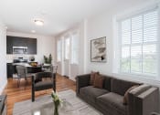 Thumbnail 9 of 20 - a living room with a couch and a chair and a kitchen with a dining room