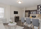 Thumbnail 7 of 20 - a living room with a kitchen and a table with chairs