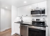 Thumbnail 17 of 37 - a kitchen with white cabinets and a stove and a microwave