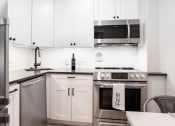 Thumbnail 14 of 37 - a white kitchen with stainless steel appliances and white cabinets