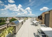 Thumbnail 17 of 41 - a rooftop patio with tables and chairs and a barbecue grill