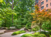 Thumbnail 8 of 41 - a park with benches and trees in front of a brick building