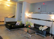 Thumbnail 14 of 28 - A black couch with a yellow pillow is in front of a white wall.