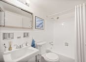 Thumbnail 12 of 19 - A white bathroom with a toilet, sink, and shower.