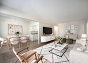 Thumbnail 6 of 15 - A modern living room with a white sofa, wooden chairs, and a coffee table.