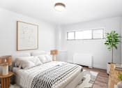Thumbnail 6 of 7 - A bedroom with a large bed and a plant on the side table.