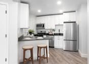 Thumbnail 7 of 7 - A kitchen with white cabinets and a grey floor.